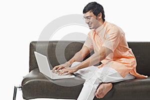 Bengali man using a laptop on the couch