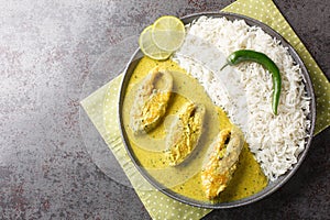 Bengali Shorshe Ilish or Hilsa cooked in Mustard Gravy served with white rice closeup on the plate. Horizontal top view