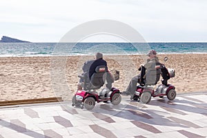 Benidorm, Spain - January 14, 2018: Seniors on mobility scooters looking to the sea in Benidorm, Spain