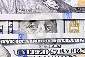 Benjamin Franklin`s eyes between hundred dollar banknotes close-up. 100 dollar bill with only eyes of Benjamin Franklin