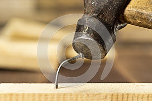 The bent nail sits on a hammer, a metalwork workshop