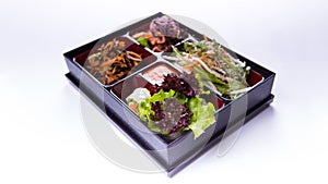 Bento box salad of lettuce, cabbage and kimchi on white background