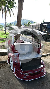 Bentor modified scooter that is used to transport people as a taxi.Widespread on Sulawesi in the city of Kotamobag. Red motorbike.