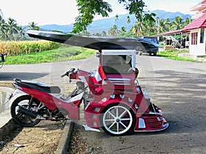 Bentor modified scooter that is used to transport people as a taxi.Widespread on Sulawesi in the city of Kotamobag.Red motorbike.