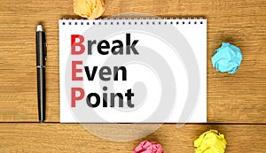 BEP break even point symbol. Concept words BEP break even point on white note on a beautiful wooden table wooden background. Pen.