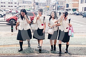 Four Japanese Schoolgirls crossing the street.Heat in the city