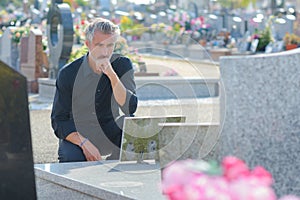 bereaved man staring sadly at gravestone