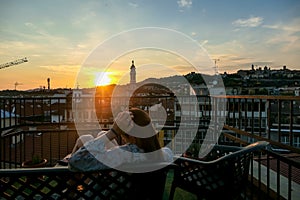 Bergamo - Relaxed woman with scenic sunset view of tower of  church Chiesa di Sant Alessandro della Croce, Italy