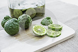 Bergamot fruit cutting slices on wooden clipping board on sackcloth background. Bergamot material of essential oils for beauty and