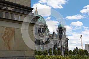 Berlin Cathedral seen from behind a marble column. Light blue dome with gold appliquÃ©s. Celestial sky with white pompous clouds