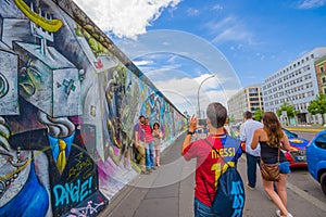 BERLIN, GERMANY - JUNE 06, 2015: Turists taking photographs on graffiti Berlin wall, ways to express theirselves