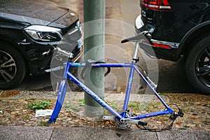 Berlin, October 2, 2017: Blue bicycle attached to street pillar with lock stands without wheels after being stolen in