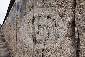 Berlin Wall original weathered section damaged with exposed iron bars and rough cement concrete texture