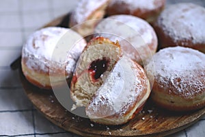Berliner donuts in powdered sugar on a wooden tray