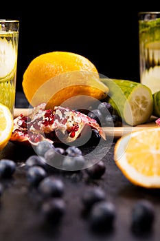 Berried, pomegranate and lemons on dark wooden background