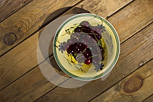 Berries cherry, behind the plate, standing on a wooden background.