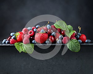 Berries closeup colorful assorted mix on a dark stone background