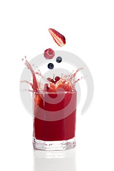 Berries falling into glass with red fruit juice