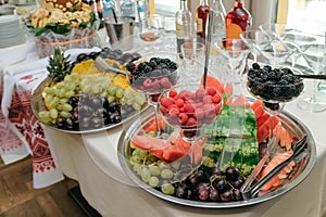 Berries and fruits in a glass dish and a tray on banquet table