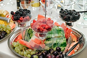 Berries and fruits in a glass dish and a tray on banquet table