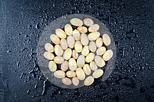 Berries of home-made white grapes in the form of a circle on a black wooden background in drops of water