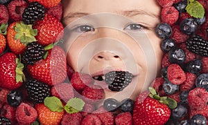 Berries with kids face close-up. Top view of child face with berri. Berry set near kids face. Cute little boy eats