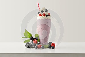 Berries milkshake with cream decorated with fruit on table isolated