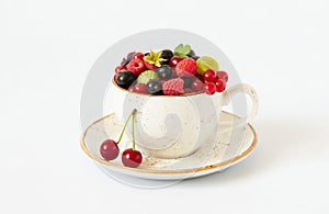 Berries in a mug on a white background. Cherries, raspberries, gooseberries and red currants in a cup. Juicy fresh berries