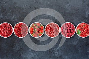 Berries in plates on a black concrete background. Copy space. Flat top view