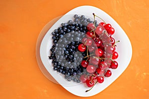 berries of ripe cherries and blueberries on a plate, summer seasonal berries