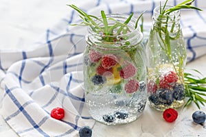 Berries and tarragon in jar with sparkling ice water.