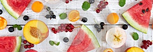 Berry background. Many summer fruits and berries are scattered on a white wooden background