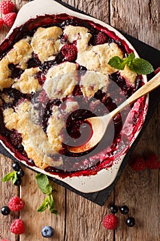Berry cobbler with currants, raspberries and blueberries decorated with mint close up. vertical top view