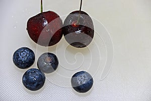 Berry fruit and cherry on the white floor. Berry is a small roundish juicy fruit.