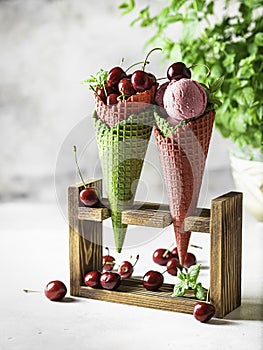 Berry ice cream in a waffle cone on a light background. Cherry ice cream. Ice cream cone with cherry, sweet cherry