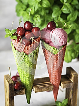 Berry ice cream in a waffle cone on a light background. Cherry ice cream. Ice cream cone with cherry, sweet cherry