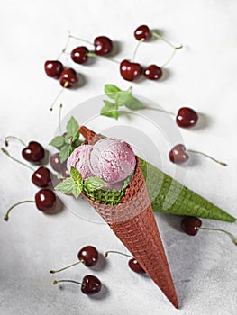 Berry ice cream in a waffle cone on a light background. Cherry ice cream. Ice cream cone with cherry, sweet cherry