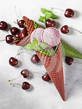 Berry ice cream in a waffle cone on a light background. Cherry ice cream. Ice cream cone with cherry, sweet cherry