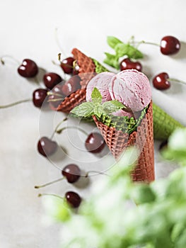 Berry ice cream in a waffle cone on a light background. Cherry ice cream. Ice cream cone with cherry, sweet cherry