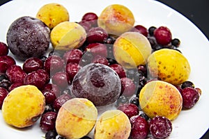 A Berry mix from frozen currant, apricot, plum, cherry. A Frozen Berries from freezer. A sweet background with frozen plum,