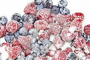 A Berry mix in sugar from frozen raspberries and blueberries. A Frozen Berries with Sugar.  A sweet background with frozen