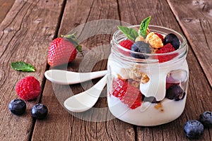 Berry parfait in a mason jar on rustic wood background