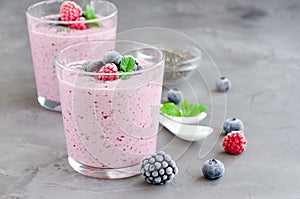 Berry smoothies of yogurt, chia seeds and frozen berries in a glass on a dark concrete background. Healthy food. Copy space