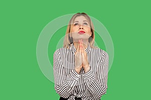 Beseeching woman with beautiful red lips and in blouse holding hands together while praying