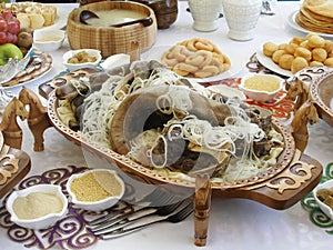 Beshbarmak - Kazakh national dish on a carved wooden platter. Festive table