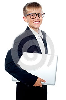 Bespectacled young boy carrying a laptop