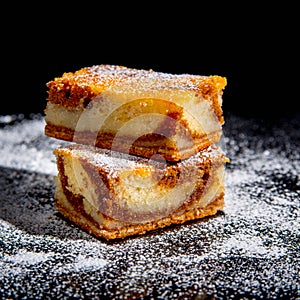 Besquit, cake on a black background, sprinkled with powdered sugar, dark and light layer of beckett on a black background, copy