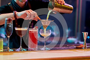Best alcohol here. Close up of hands of male bartender pouring, mixing ingredients while making cocktails, alcoholic