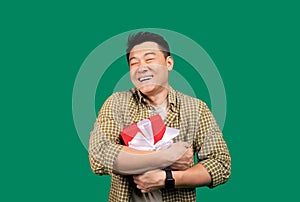 Best birthday gift. Happy asian man hugging wrapped present box and smiling over green studio background