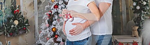Best Christmas gift. Young pregnant woman with her husband standing by Christmas tree at home.pregnancy, love, holidays